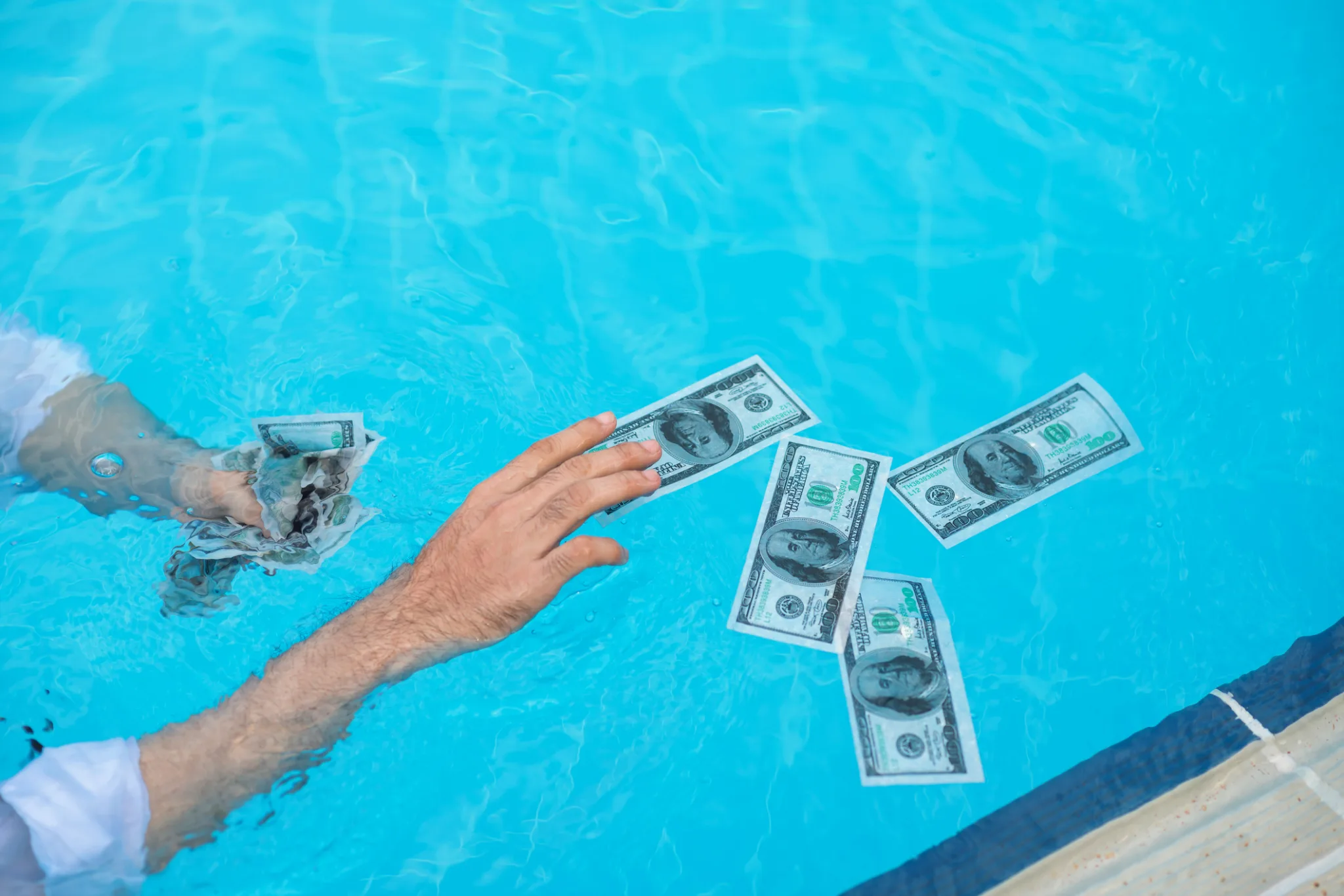 Male hands catching money in the swimming pool